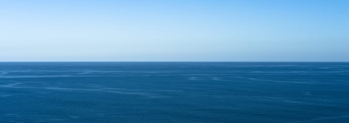 A calm, blue ocean. Half of image is sky, half is water.